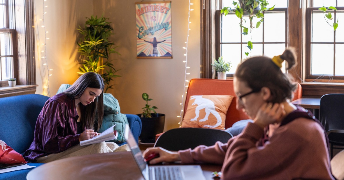 two people studying on couches and at a table with windows in the back