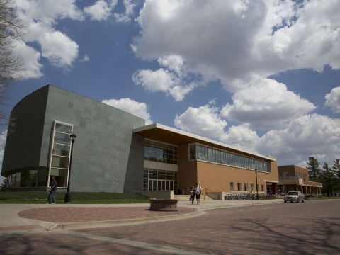 The exterior of the Rosenfield Center under a blue sky with fluffy white clouds