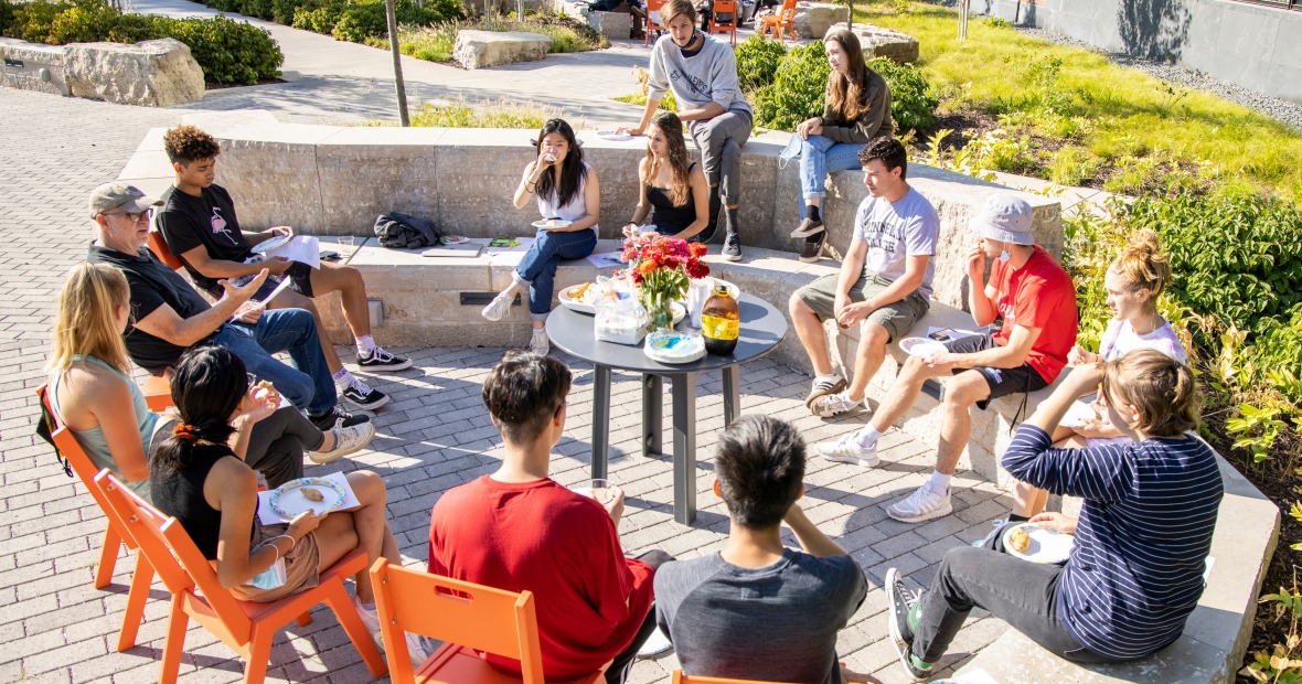 A group of students and their professor enjoy an outdoor class