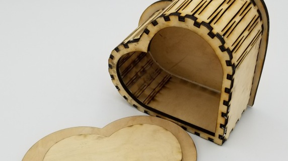 Heart-shaped box with dark marks on the curves of the wood from the laser cutting process.